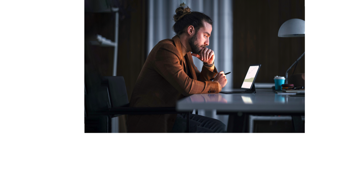 Mann mit langem Haar im dunklen Raum vor einem Laptop