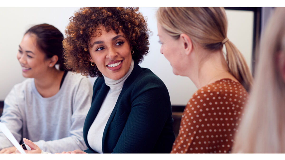 Drei Frauen im Gespräch am Schreibtisch