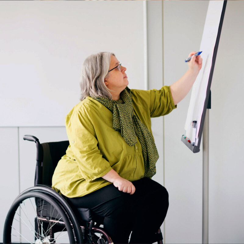 Frau im Rollstuhl schreibt auf Flipboard