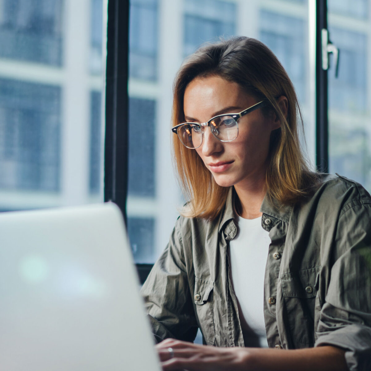 Frau mit blondem Haar sitzt vor Laptop