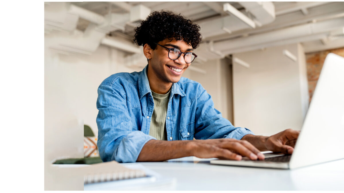 Young man in denim shirt writes on laptop