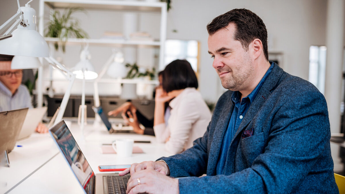 Mann in offenem Büro am Laptop