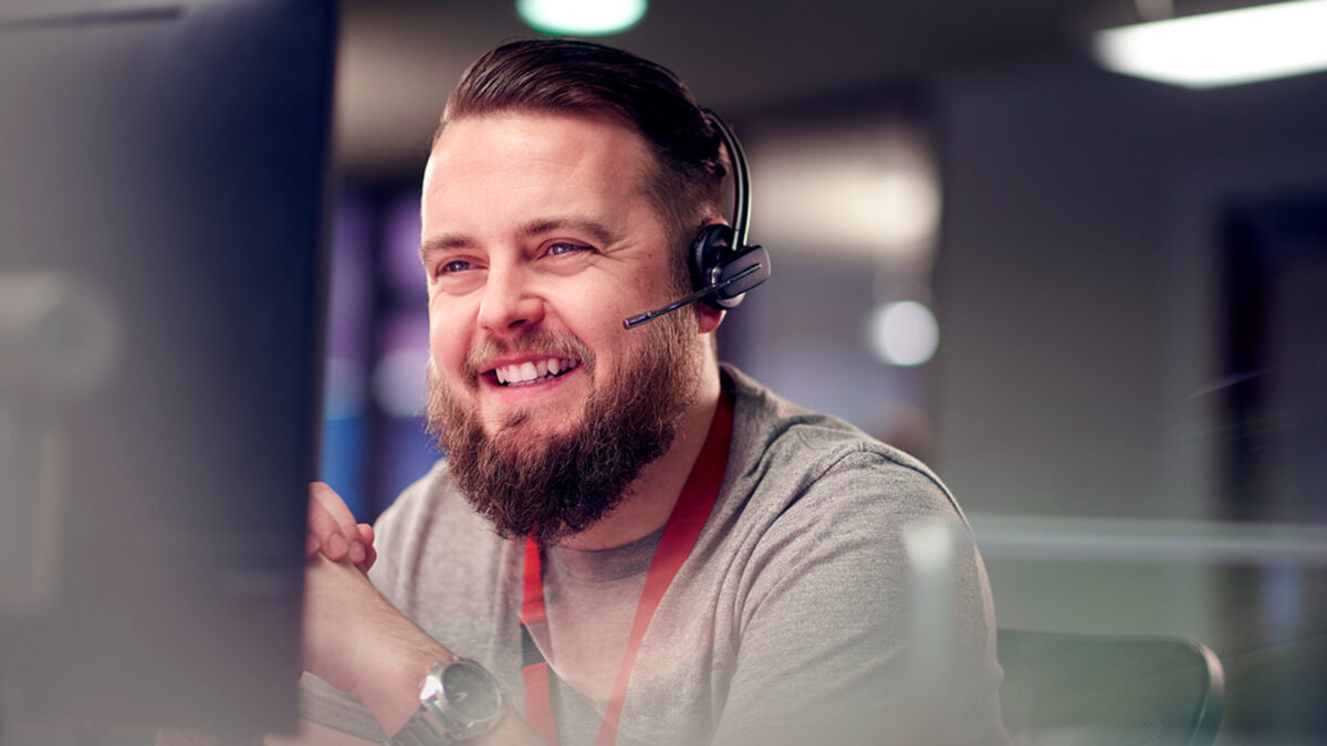 Man with headset smiles at PC