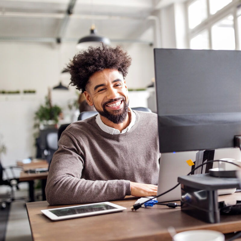 Mann mit braunem Pulli am Arbeitsplatz