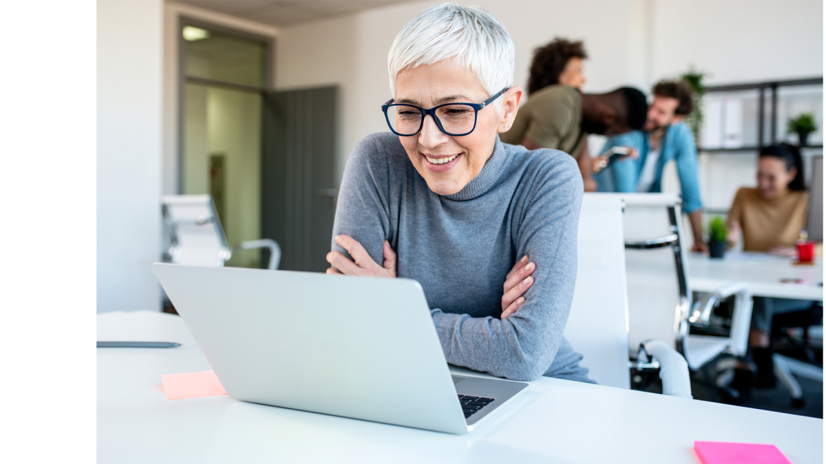 Older woman with glasses sits in front of laptop