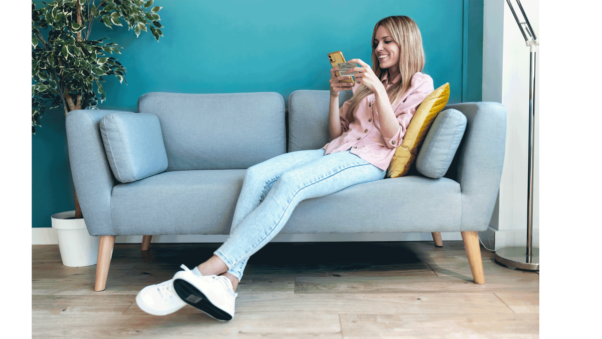 Blonde Frau liegt auf der Couch mit Personalausweis in der Hand