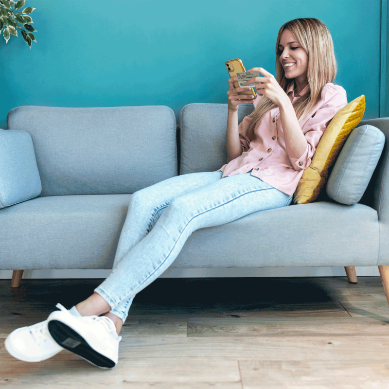 Blonde Frau liegt auf der Couch mit Personalausweis in der Hand