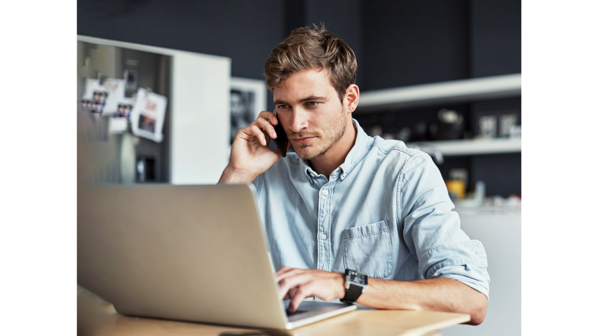 Man works on laptop and makes phone calls in home office